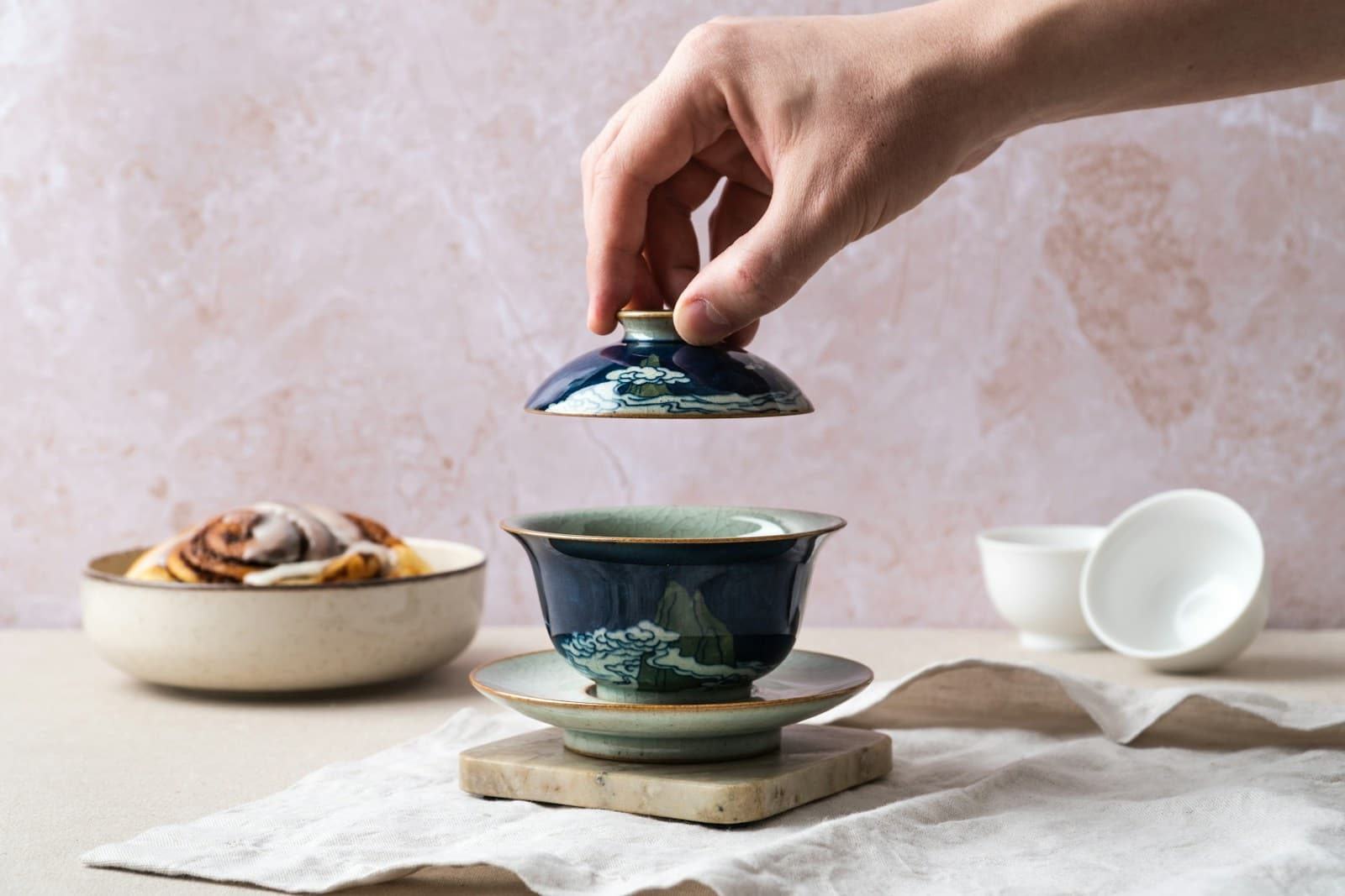 Lifting the lid of a porcelain gaiwan; tea-themed photography